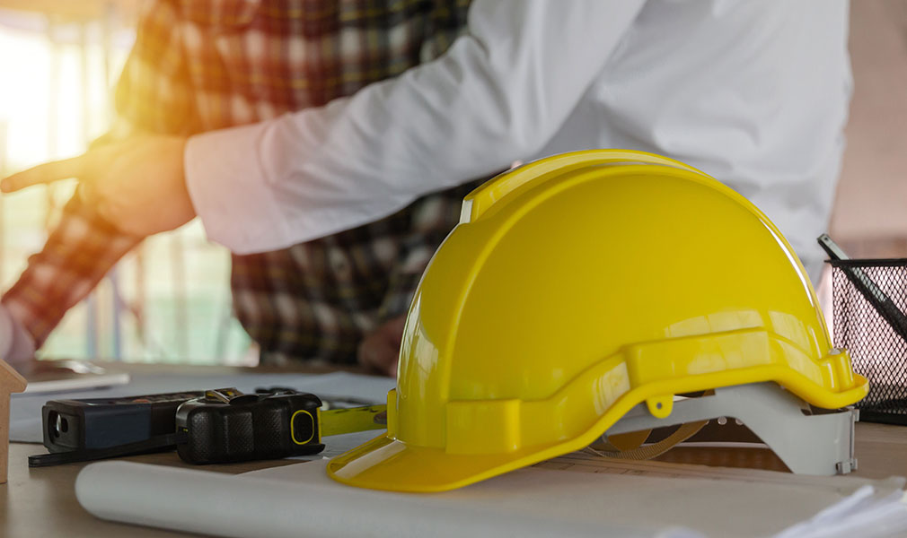 yellow safety helmet on workplace desk with construction worker